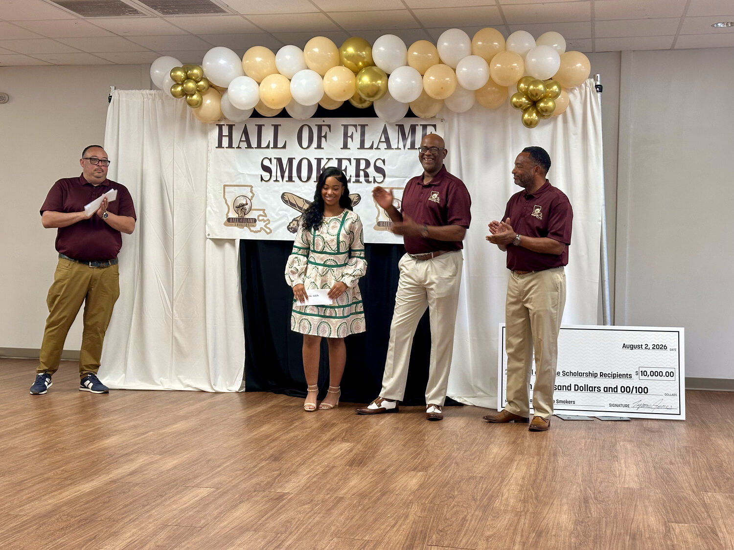 A 2026 Hall of Flame scholarship recipient presented with a $1,000 award by club members