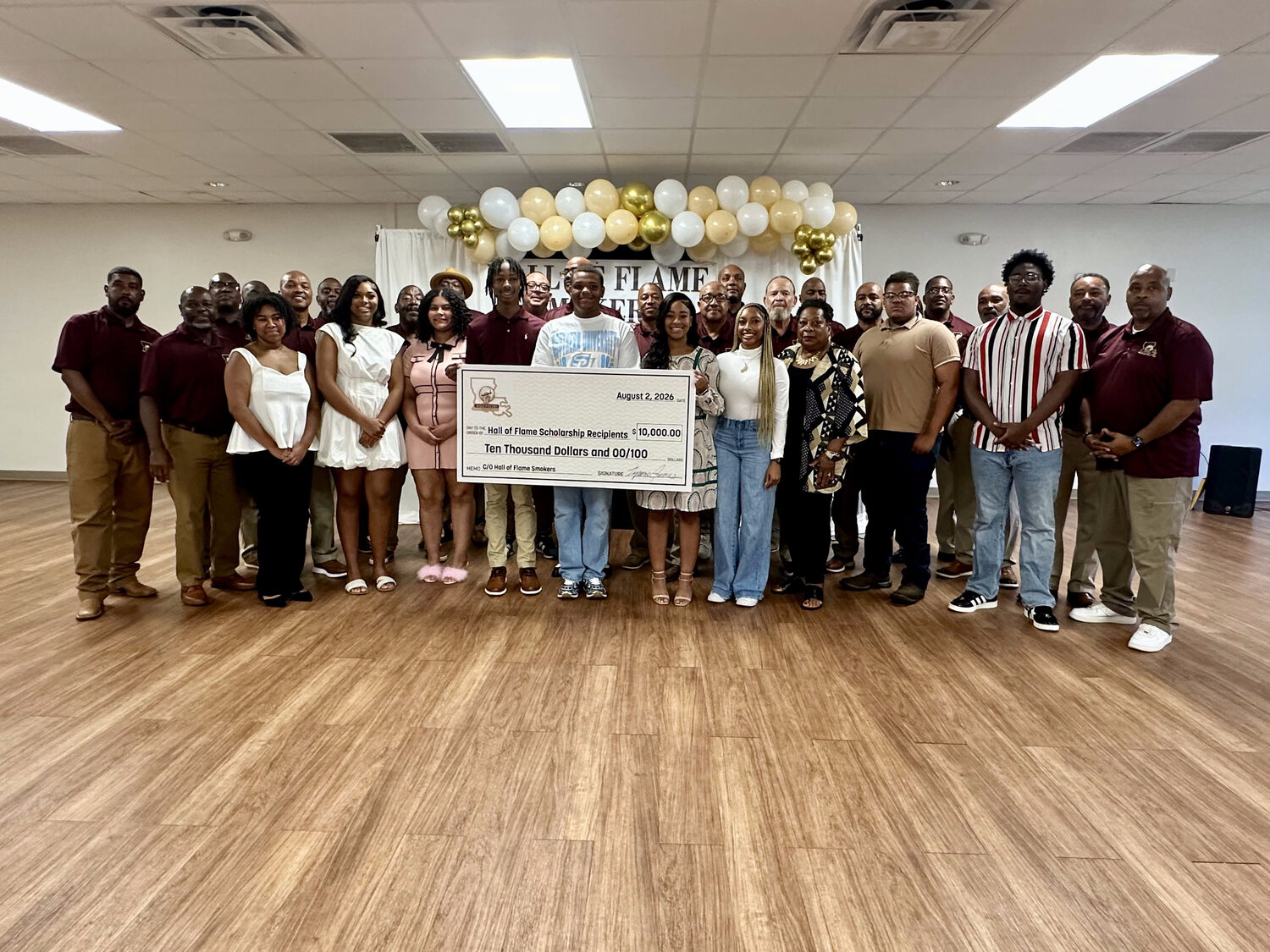 The full group of Hall of Flame Smokers, all ten scholarship recipients, and their families with the $10,000 ceremonial check at the 2026 banquet in St. Martinville